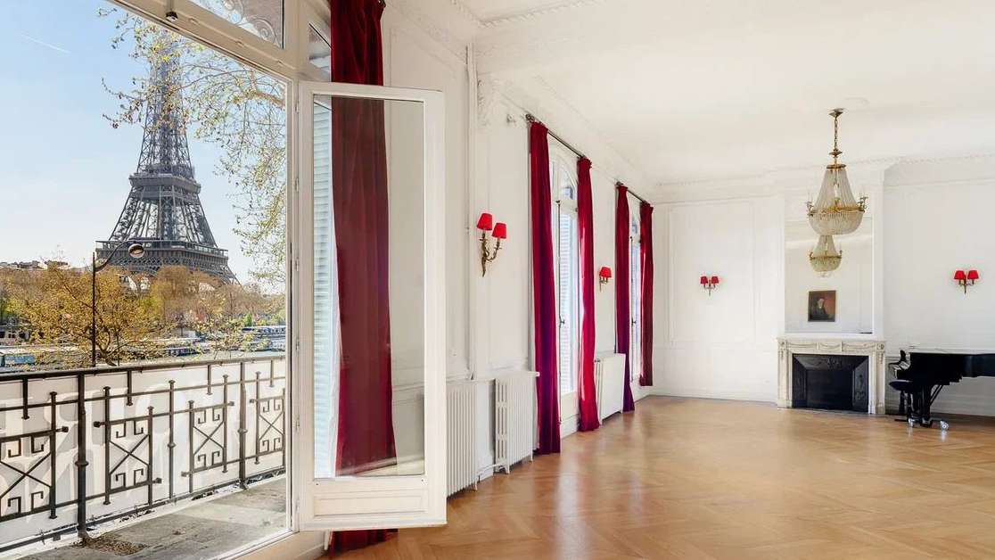 Grande Salle with red velvet curtains open to a view of the Eiffel Tower